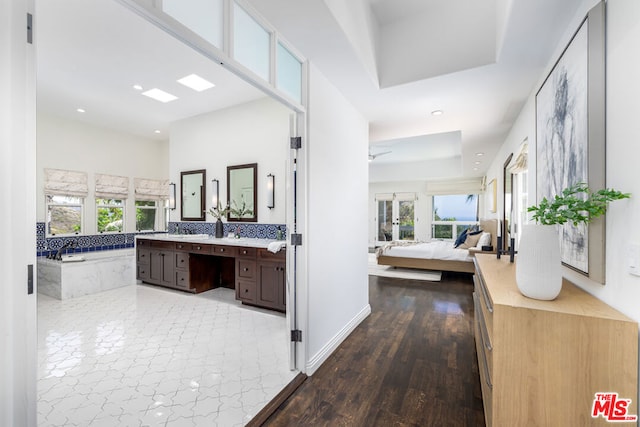 bathroom with wood-type flooring, backsplash, vanity, a washtub, and a tray ceiling