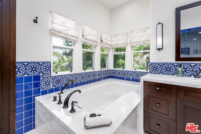 bathroom featuring a relaxing tiled tub, vanity, and a wealth of natural light