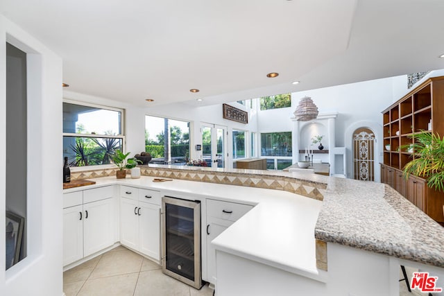 kitchen with white cabinetry, a wealth of natural light, wine cooler, and light tile patterned floors