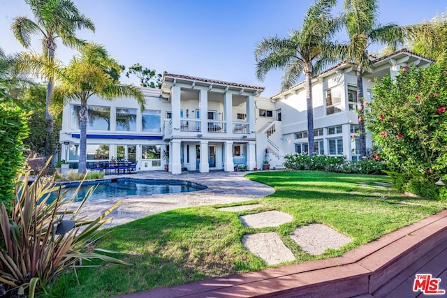 back of house with a lawn, a patio, and a balcony