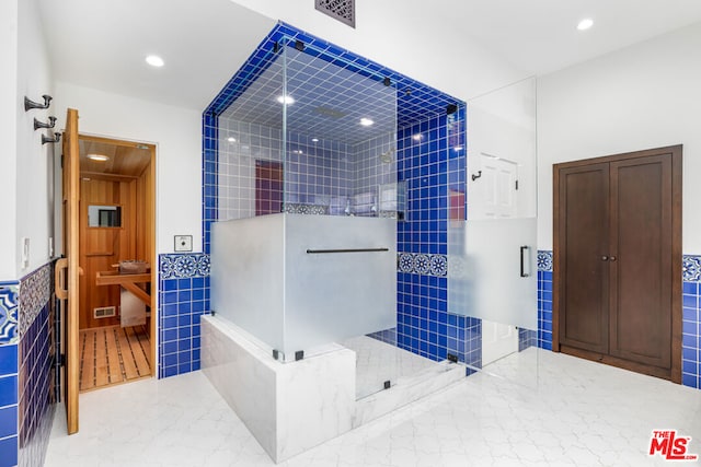 bathroom with tiled shower and tile walls