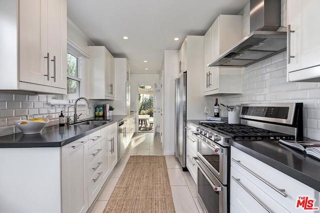 kitchen with wall chimney exhaust hood, sink, white cabinetry, light tile patterned floors, and appliances with stainless steel finishes