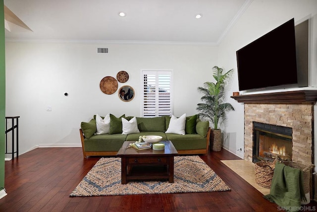 living room featuring dark hardwood / wood-style flooring, crown molding, and a stone fireplace