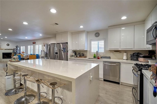 kitchen featuring appliances with stainless steel finishes, sink, a breakfast bar area, white cabinets, and plenty of natural light