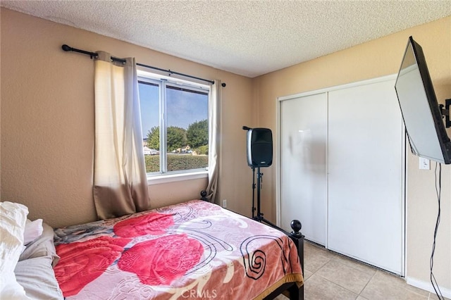 tiled bedroom with a closet and a textured ceiling