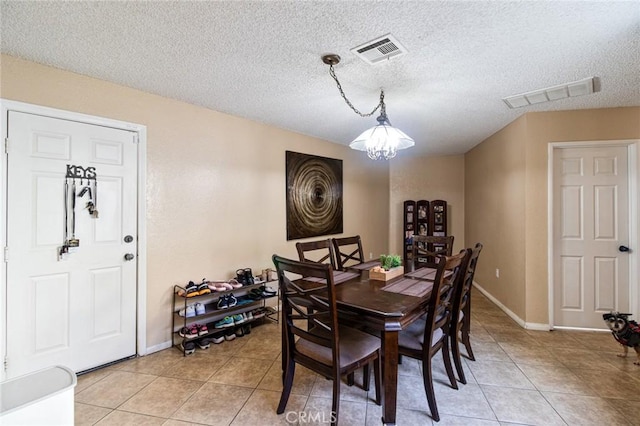 tiled dining space with a notable chandelier and a textured ceiling