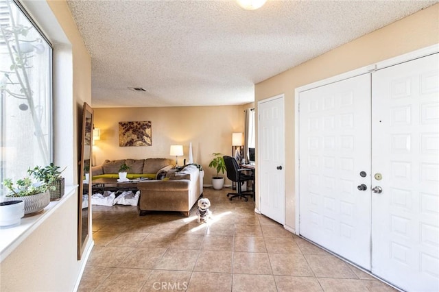 foyer entrance with a wealth of natural light, a textured ceiling, and light tile patterned floors