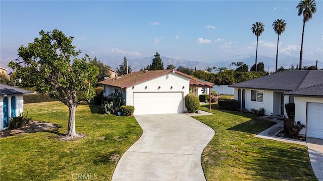 view of front of property with a garage, a mountain view, and a front lawn