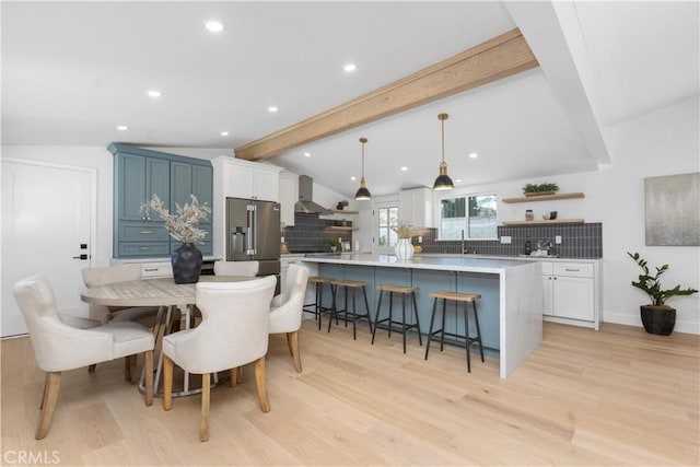 kitchen featuring high quality fridge, a breakfast bar, decorative light fixtures, lofted ceiling with beams, and white cabinetry