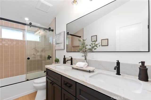 full bathroom featuring vanity, toilet, and combined bath / shower with glass door