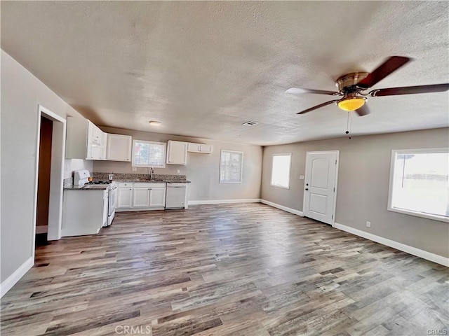 unfurnished living room featuring ceiling fan, sink, and light wood-type flooring