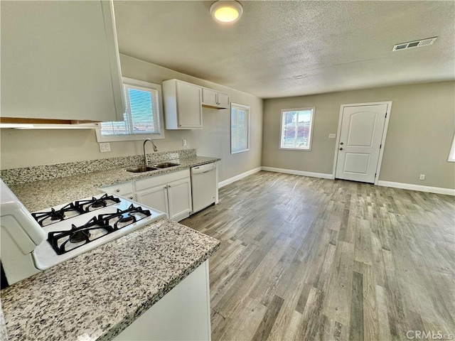 kitchen featuring dishwasher, sink, light stone countertops, and white cabinets