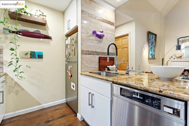 kitchen with appliances with stainless steel finishes, white cabinetry, sink, dark hardwood / wood-style flooring, and light stone counters