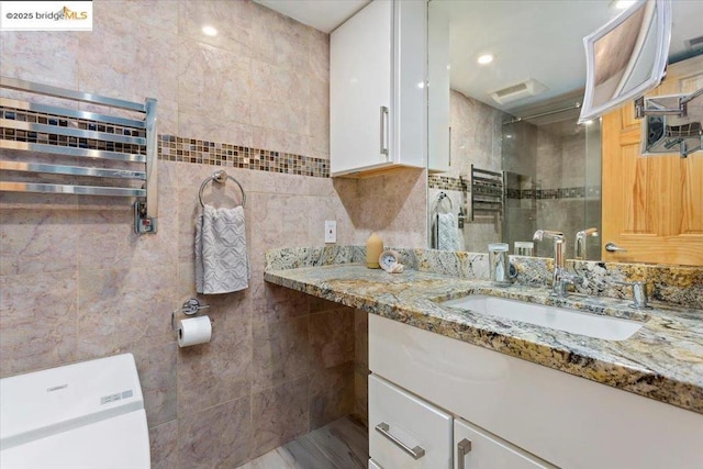 bathroom with vanity, tile walls, walk in shower, and toilet