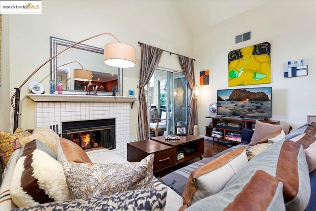 living room with a tiled fireplace, wood-type flooring, and lofted ceiling