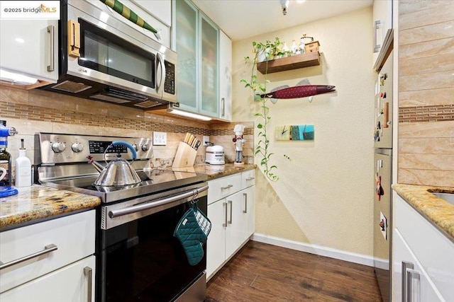 kitchen featuring white cabinetry, stainless steel appliances, light stone counters, and backsplash