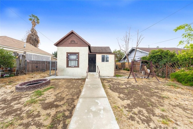 bungalow-style house with a playground and an outdoor fire pit