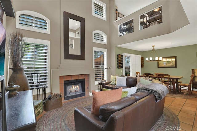 living room with an inviting chandelier, tile patterned floors, a fireplace, and a high ceiling