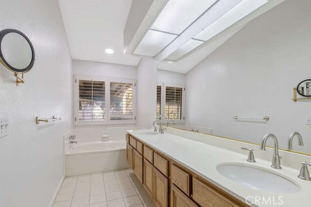 bathroom with vaulted ceiling, vanity, a tub, and tile patterned floors