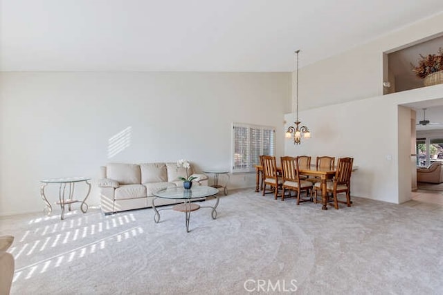 carpeted living room featuring lofted ceiling and a chandelier