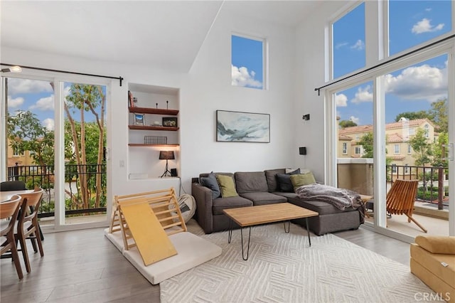 living room with a healthy amount of sunlight, a towering ceiling, and light wood-type flooring