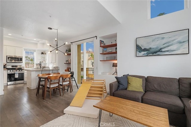 living room featuring dark hardwood / wood-style flooring, built in shelves, and a chandelier