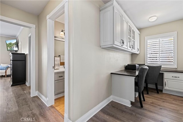 office area featuring ornamental molding, dark hardwood / wood-style floors, and built in desk