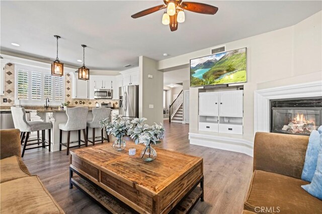 living room with hardwood / wood-style flooring, ceiling fan, and sink