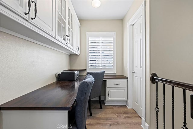 home office with wood-type flooring and built in desk