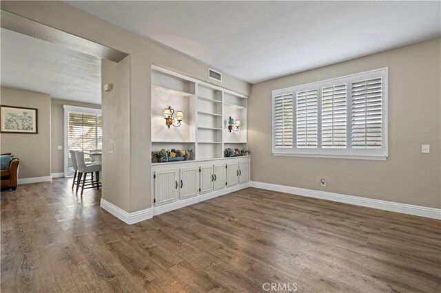 living room featuring built in shelves and wood-type flooring