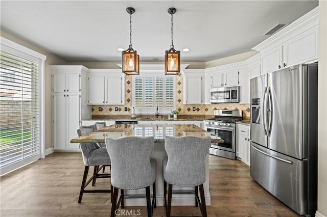 kitchen with stainless steel appliances, tasteful backsplash, a center island, and white cabinets