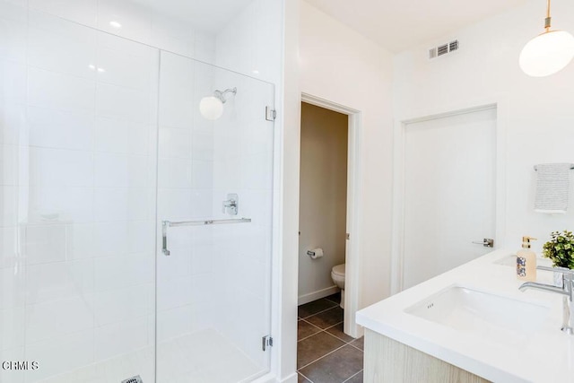 bathroom with tile patterned flooring, vanity, a shower with door, and toilet