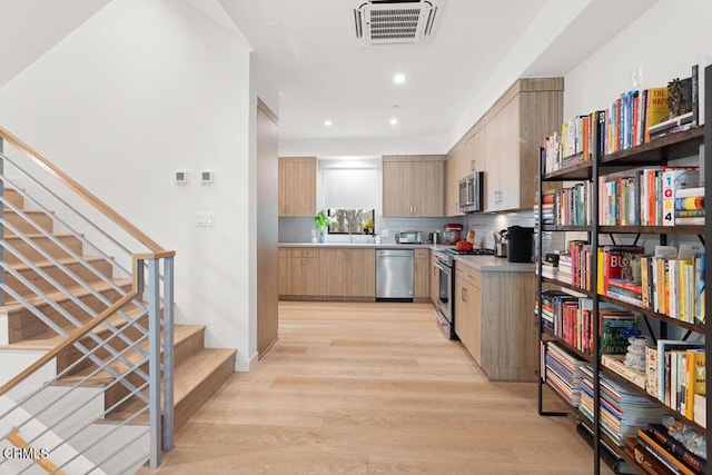 kitchen with stainless steel appliances, tasteful backsplash, light wood-type flooring, and light brown cabinetry