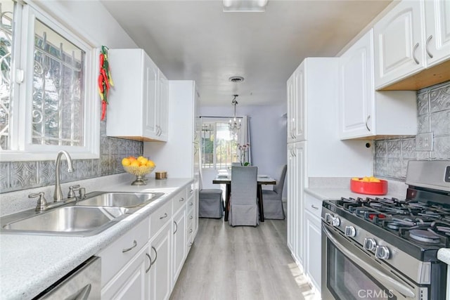 kitchen with sink, white cabinetry, hanging light fixtures, stainless steel appliances, and light hardwood / wood-style floors