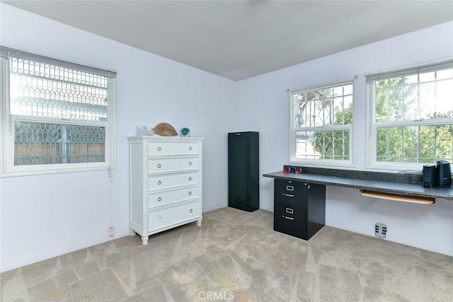 home office with light colored carpet and built in desk