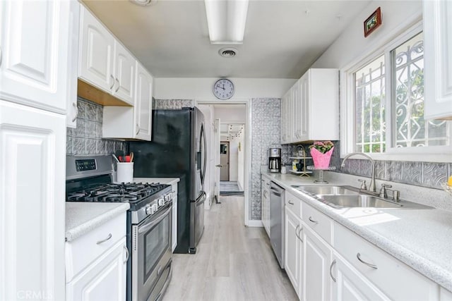 kitchen with backsplash, appliances with stainless steel finishes, sink, and white cabinets