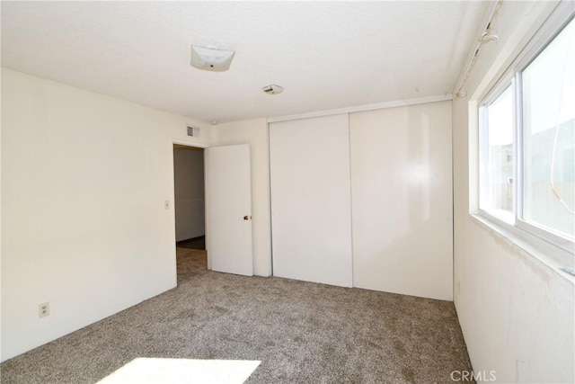 unfurnished bedroom featuring multiple windows, carpet, and a closet