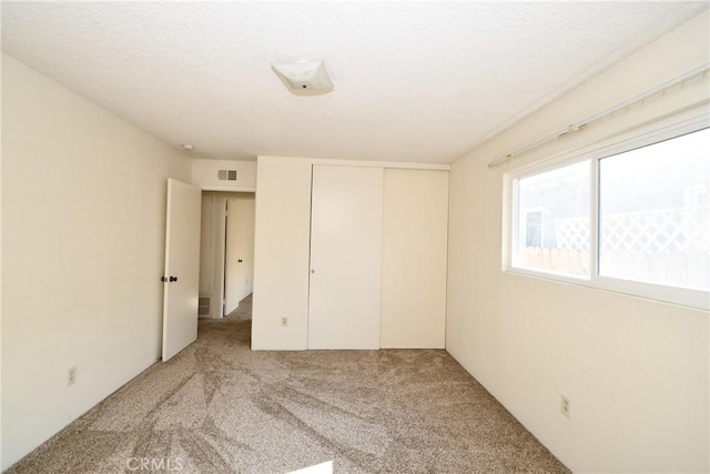 unfurnished bedroom with light colored carpet and a closet