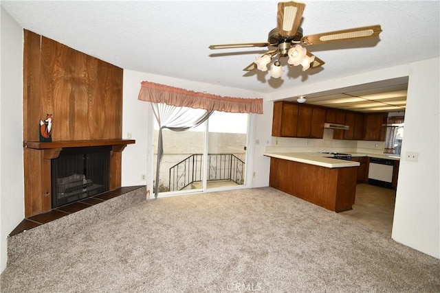 kitchen with stainless steel dishwasher, kitchen peninsula, a tile fireplace, and dark colored carpet