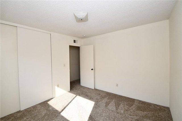 unfurnished bedroom with carpet, a textured ceiling, and a closet