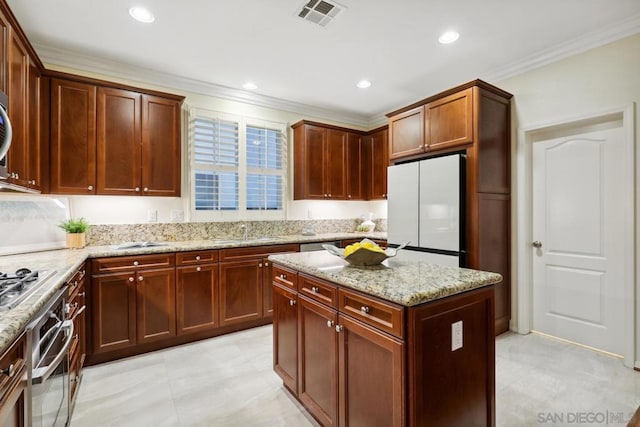 kitchen with sink, appliances with stainless steel finishes, light stone countertops, ornamental molding, and a kitchen island