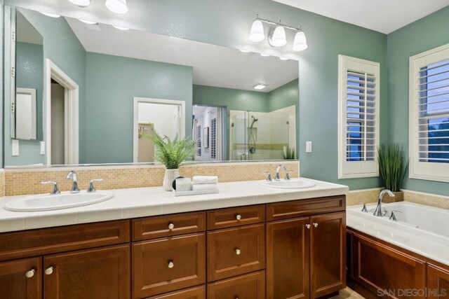 bathroom with vanity, shower with separate bathtub, and backsplash