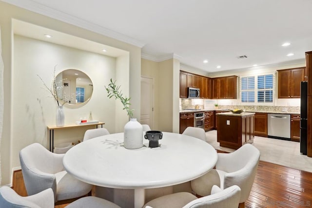 dining space with light hardwood / wood-style flooring and ornamental molding