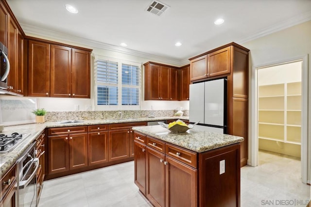 kitchen featuring sink, crown molding, a center island, stainless steel appliances, and light stone countertops