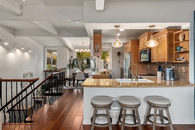 kitchen with stainless steel appliances, dark wood-type flooring, a peninsula, and tasteful backsplash