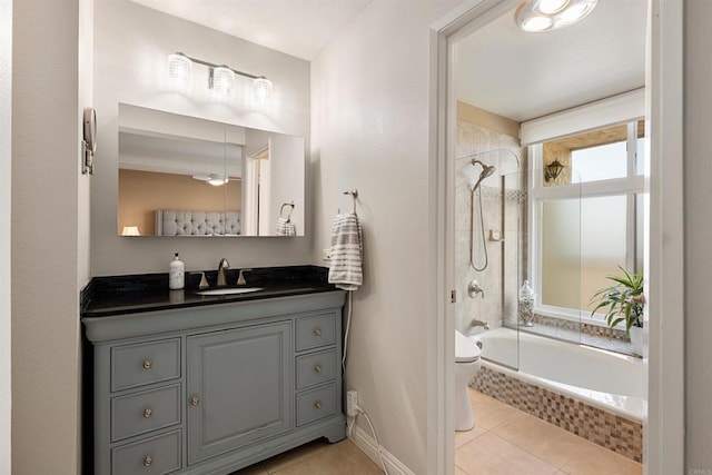 full bath with baseboards, toilet, tile patterned floors, tiled shower / bath combo, and vanity