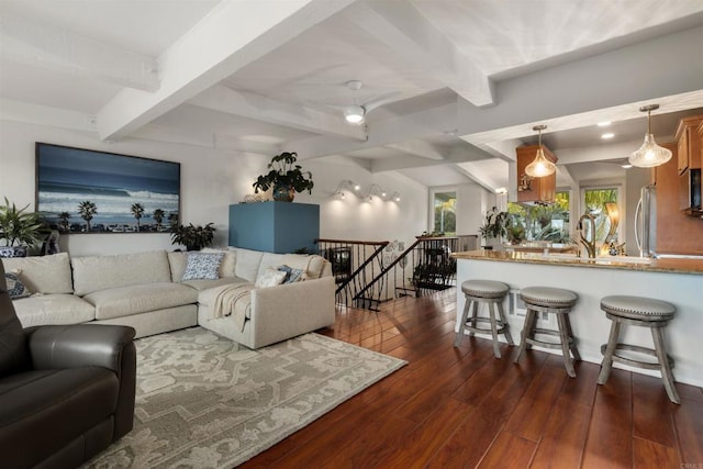 living room with a ceiling fan, dark wood-type flooring, and beamed ceiling