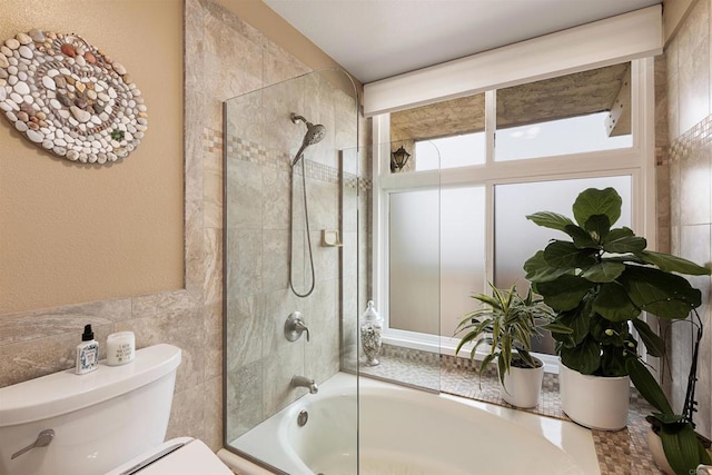 bathroom with toilet, bathtub / shower combination, and tile walls