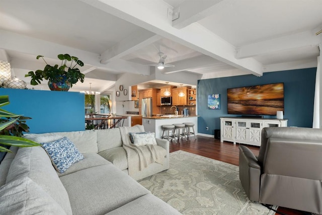 living room featuring vaulted ceiling with beams, baseboards, wood finished floors, and ceiling fan with notable chandelier