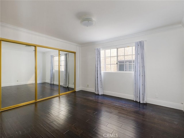 unfurnished bedroom featuring multiple windows, ornamental molding, dark hardwood / wood-style floors, and a closet